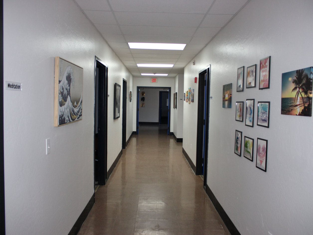 A hallway at Mana Health and Wellness, with the Meditation room and a wall of artwork