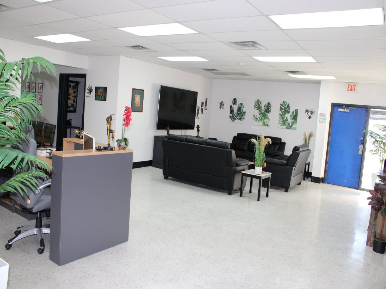 The Mana Health and Wellness reception desk and waiting area, with monstera prints and palms